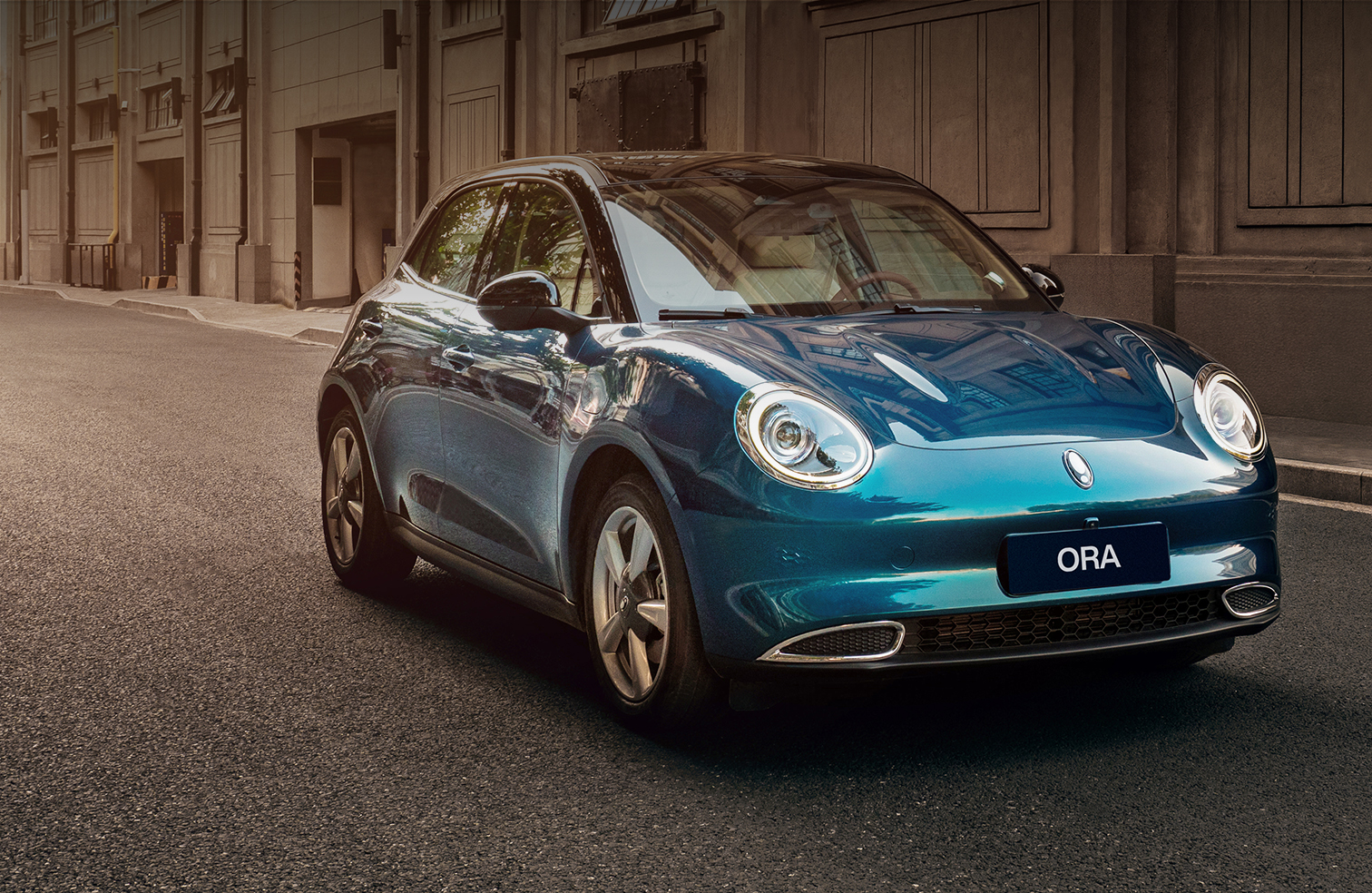 Aurora Green GWM Ora driving through a street with European style buildings