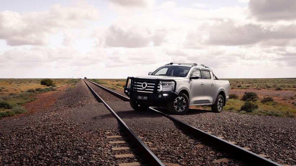 A Slate Grey GWM Ute Cannon with a black bullbar stopped on top of the train tracks
