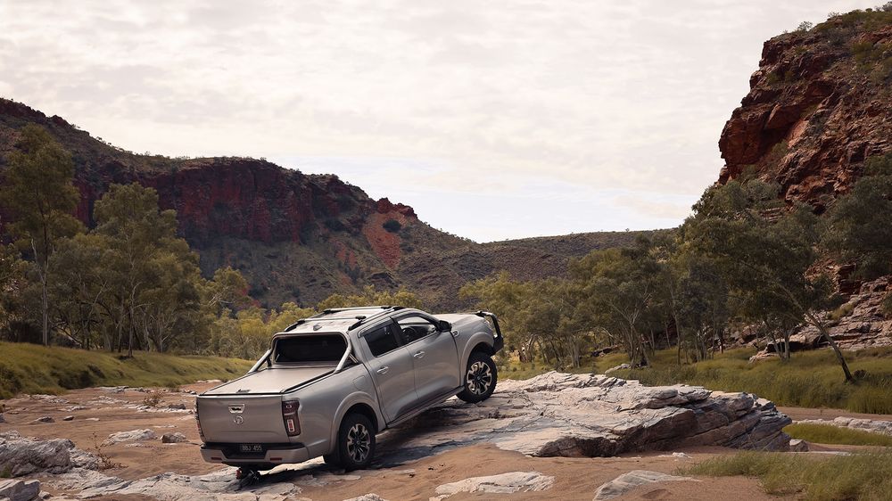 A Slate Grey GWM Ute Cannon parked on top of a large rock in between 2 rocky cliff faces