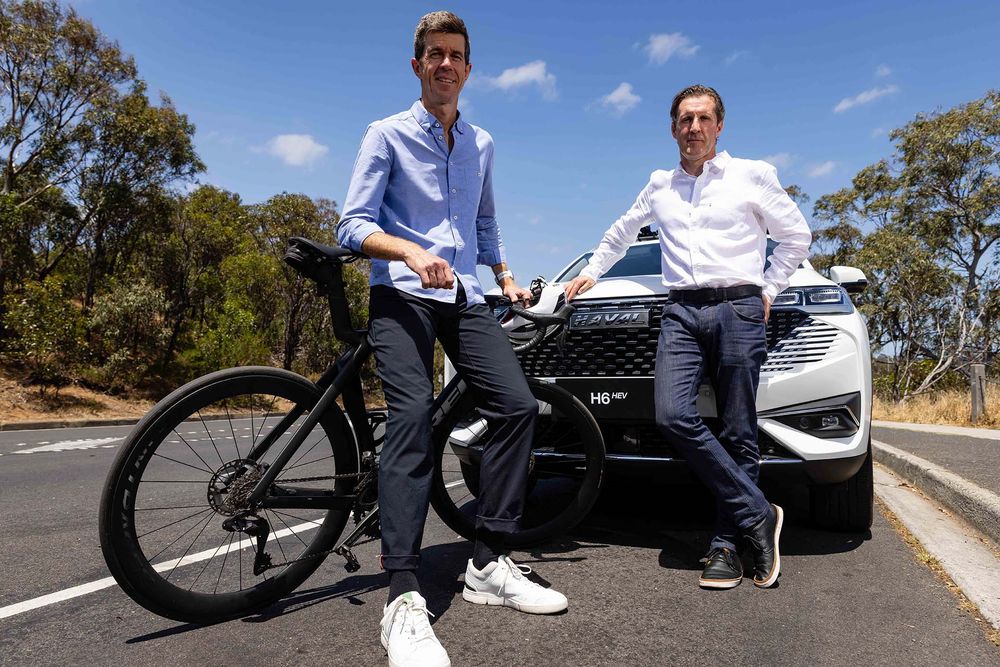 Matt Keenan leaning on his bicycle and Head of GWM Marketing Steve Maciver leaning on a Pearl White GWM Haval H6 Hybrid
