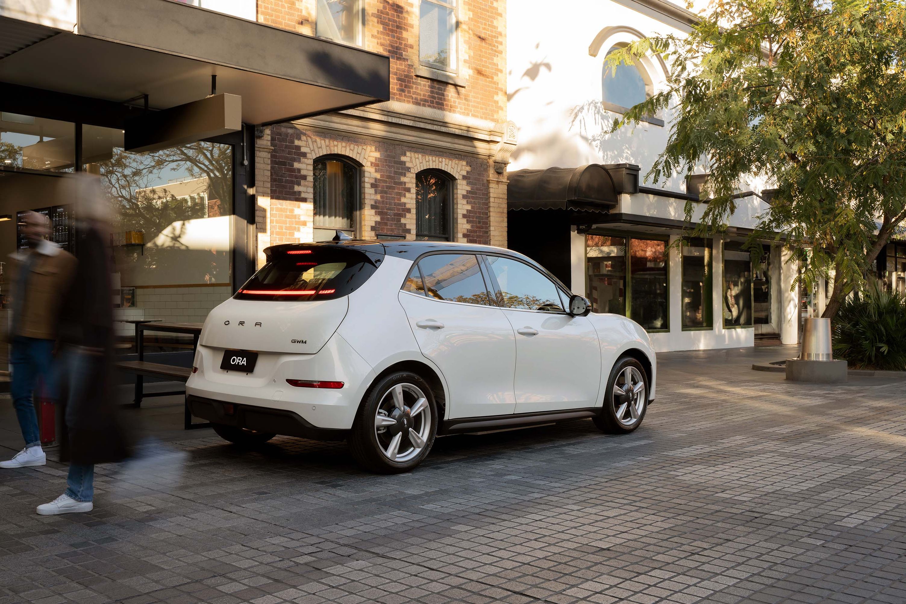 A Hamilton White GWM Ora parked on inner city paving against storefronts