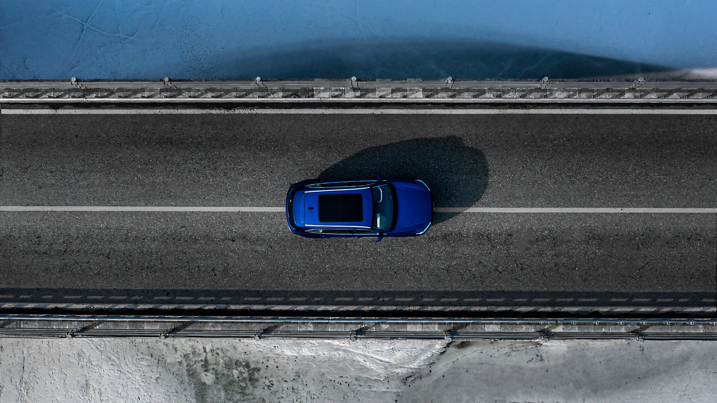 Overhead drone shot of a Sapphire Blue GWM Haval H6 driving on the road over a bridge