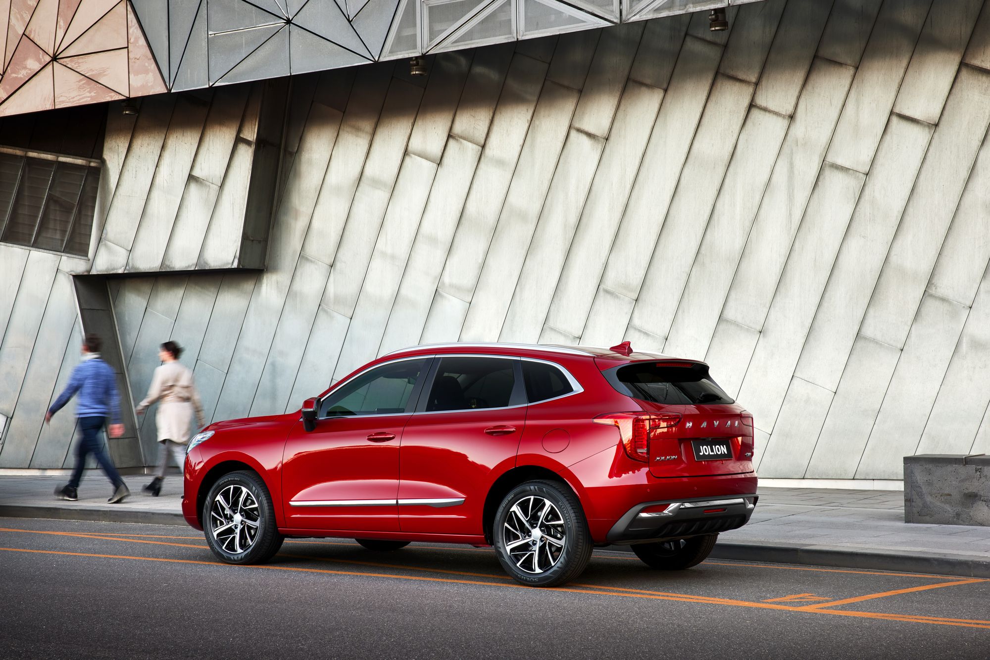 Mars Red GWM Haval Jolion parked next to a building with an isometric patterned wall cladding