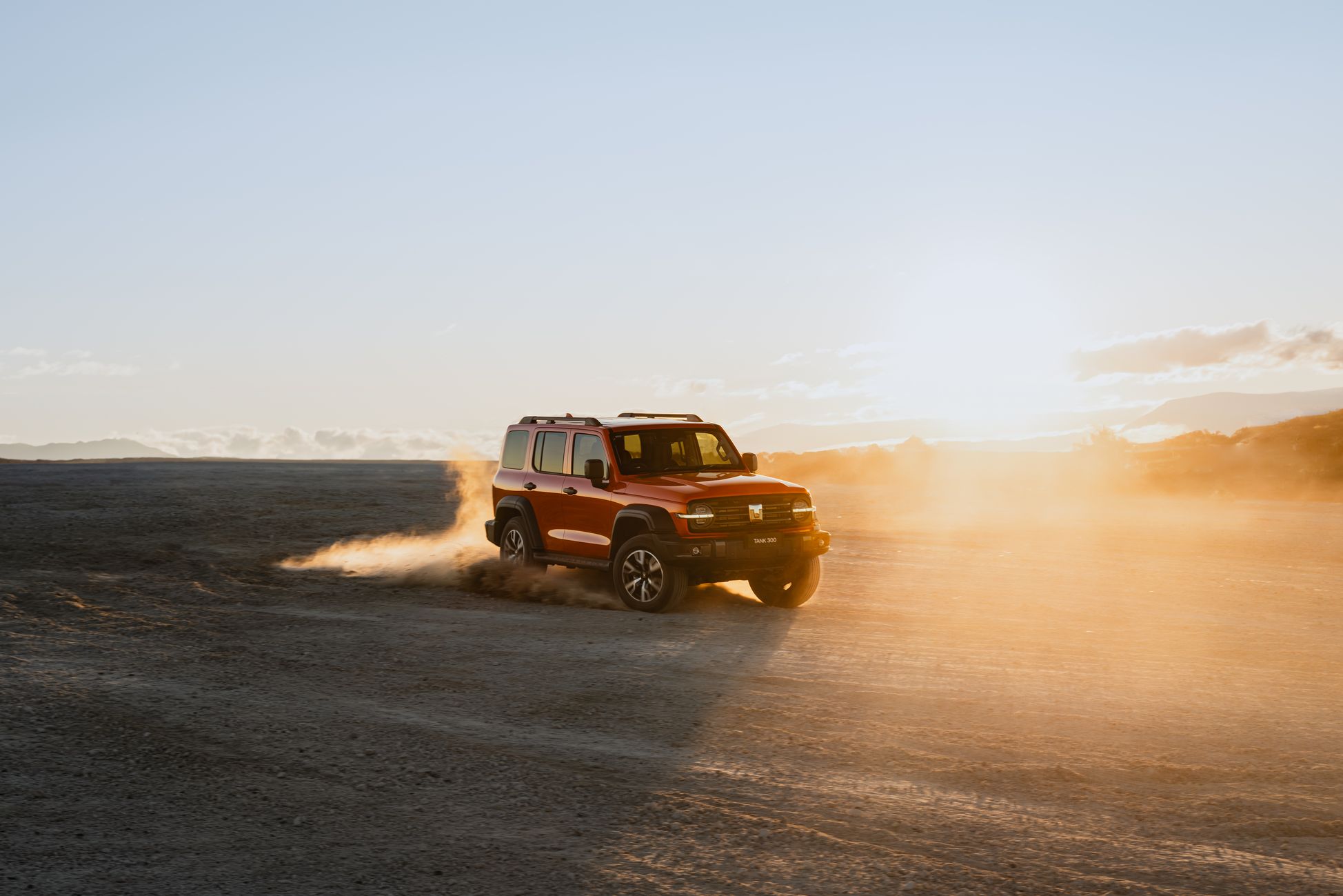 Dusk Orange GWM Tank 300 driving in the desert - kicking up sand as it's turning