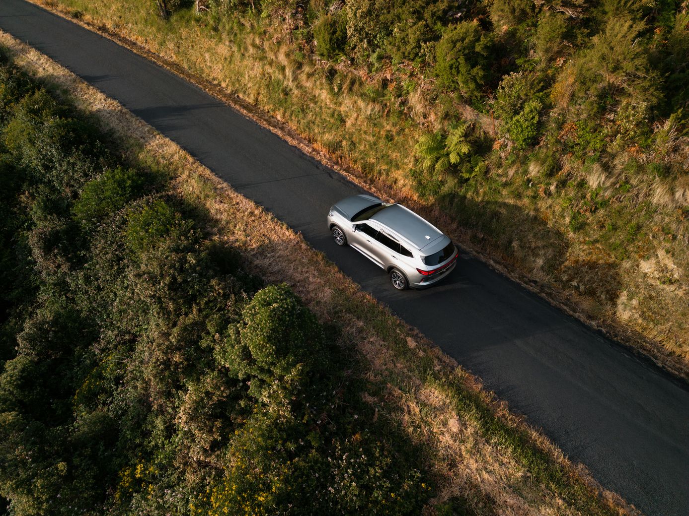 Overhead drone photo of a Ayers Grey GWM Haval H6 driving on a rural road up a hill