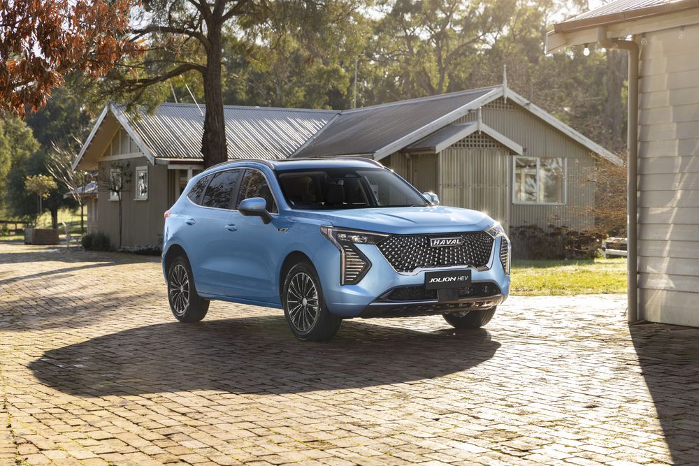 An Azure Blue Jolion Hybrid parked on the driveway next to a house on a sunny day