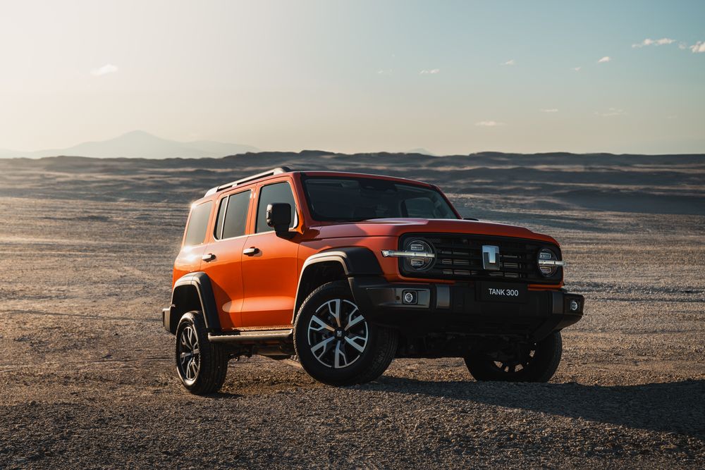 Dusk Orange GWM Tank 300 parked on gravel on top of a small hill with a desert backdrop